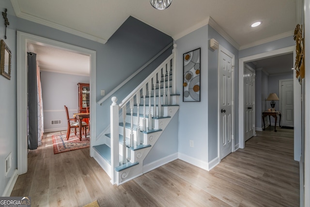 staircase with hardwood / wood-style floors and crown molding