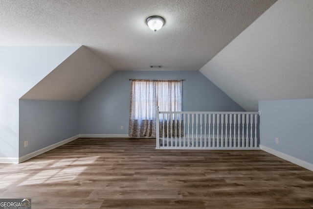 bonus room with hardwood / wood-style flooring, lofted ceiling, and a textured ceiling