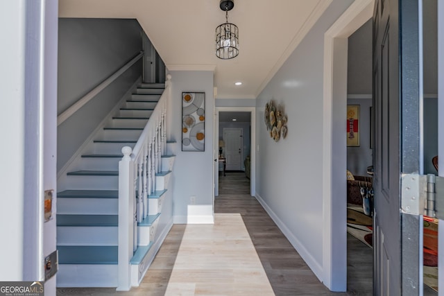 foyer entrance with crown molding, a chandelier, and light hardwood / wood-style floors