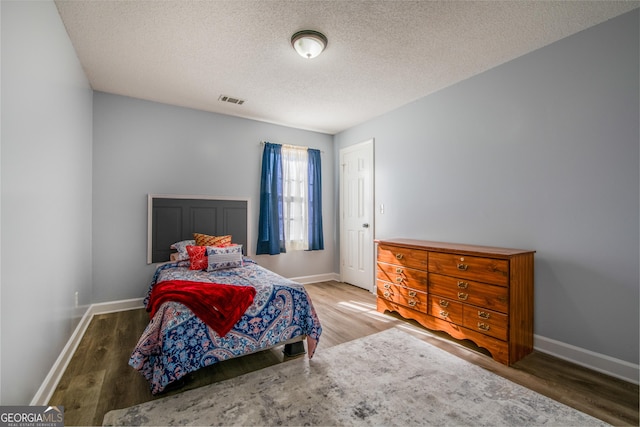 bedroom featuring wood-type flooring and a textured ceiling