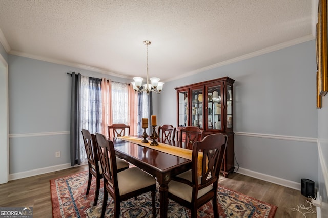 dining space featuring ornamental molding, dark hardwood / wood-style floors, a notable chandelier, and a textured ceiling