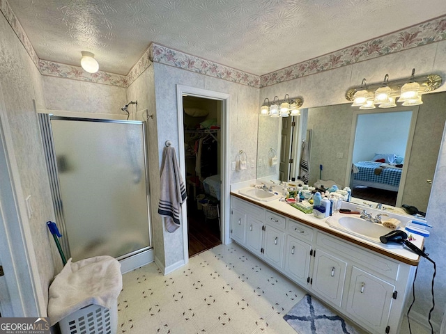 bathroom featuring an enclosed shower, vanity, and a textured ceiling