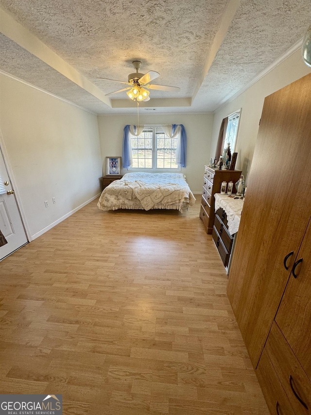 unfurnished bedroom featuring ceiling fan, a raised ceiling, a textured ceiling, and light wood-type flooring