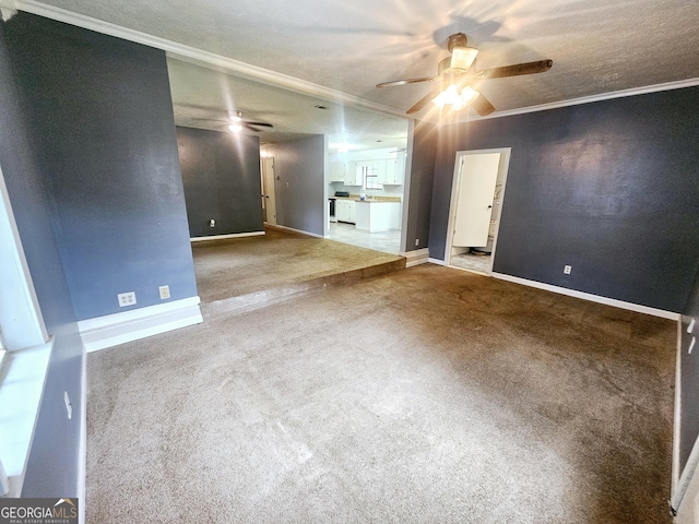 carpeted spare room with a textured ceiling, ornamental molding, and ceiling fan