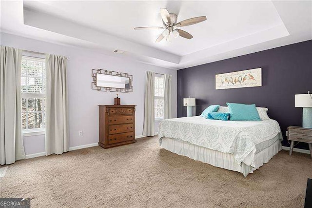 bedroom with ceiling fan, a raised ceiling, and carpet floors