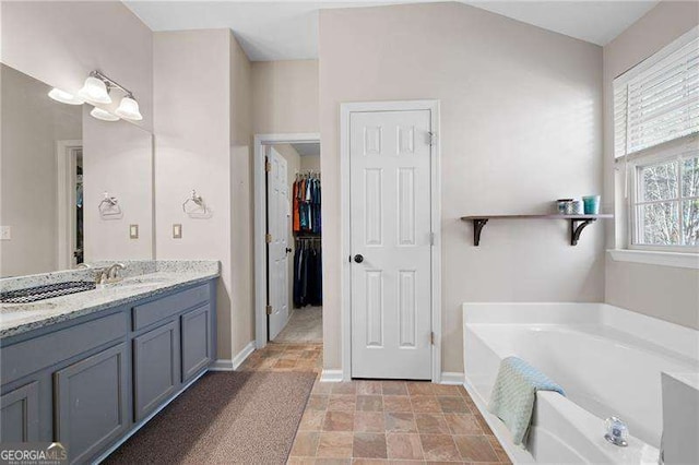 bathroom featuring vanity, vaulted ceiling, and a tub to relax in