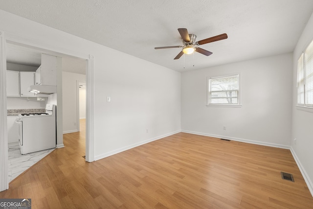 empty room featuring a textured ceiling, light hardwood / wood-style floors, and ceiling fan