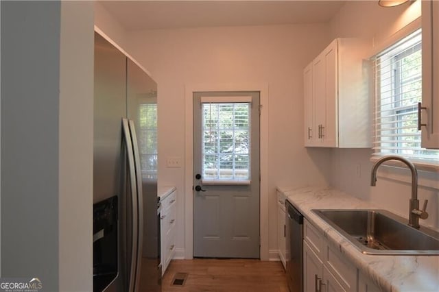 kitchen with stainless steel appliances, white cabinetry, plenty of natural light, and sink