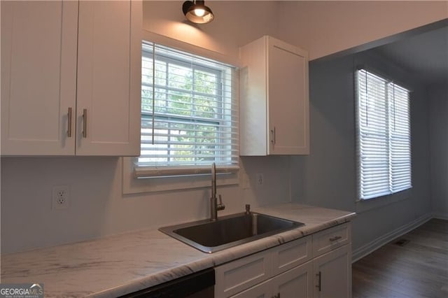 kitchen featuring plenty of natural light, light stone countertops, sink, and white cabinets