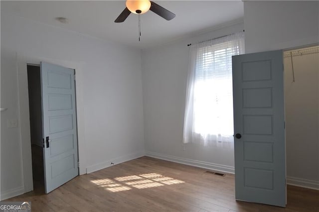 empty room with ceiling fan and light hardwood / wood-style flooring