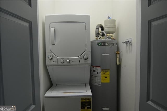 clothes washing area featuring stacked washer / dryer and electric water heater