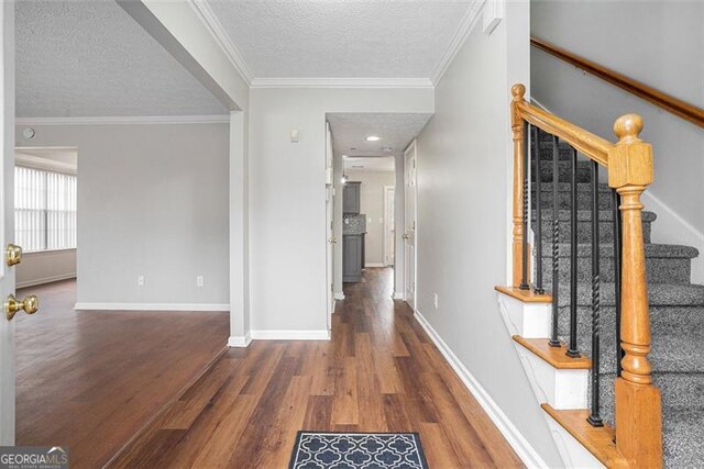 corridor with dark wood-type flooring, ornamental molding, and a textured ceiling