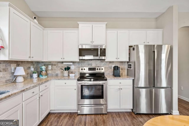 kitchen featuring stainless steel appliances, white cabinetry, and light stone countertops