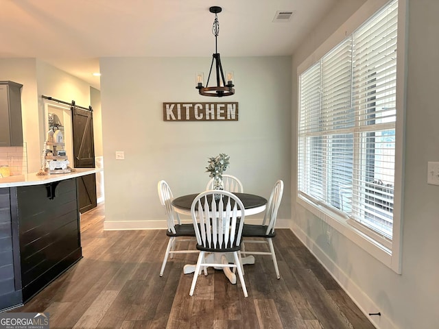 dining room featuring a barn door, dark hardwood / wood-style floors, and a notable chandelier