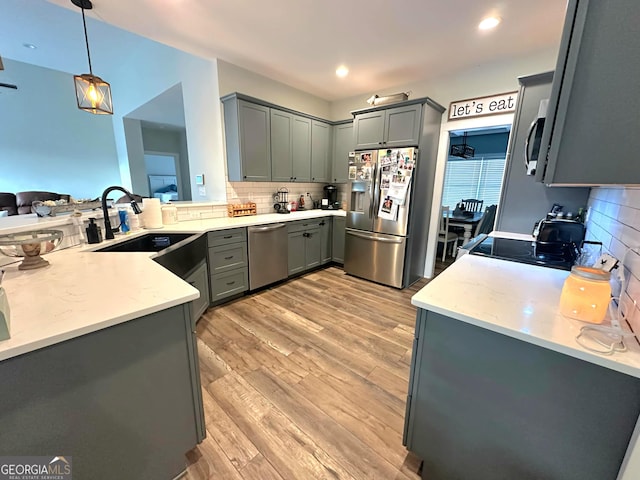 kitchen with pendant lighting, light wood-type flooring, stainless steel appliances, and gray cabinetry