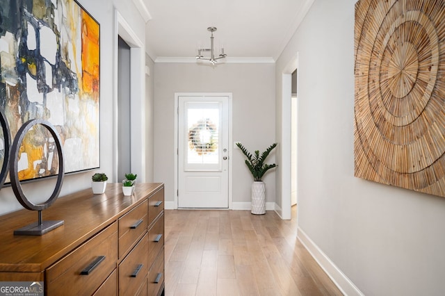 doorway featuring a chandelier, light wood-style floors, baseboards, and ornamental molding
