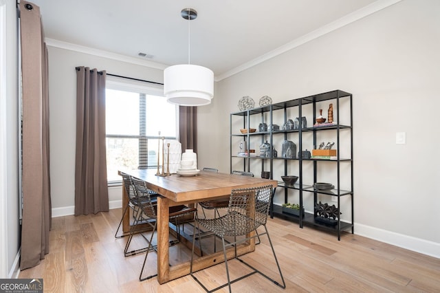 dining area with baseboards, crown molding, visible vents, and light wood-style flooring