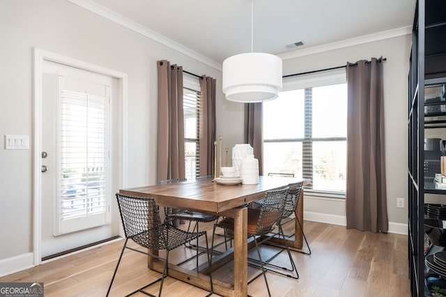 dining space with baseboards, crown molding, visible vents, and light wood-style flooring