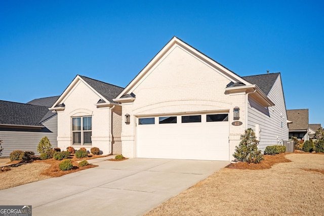 ranch-style home featuring central air condition unit, driveway, brick siding, an attached garage, and a shingled roof