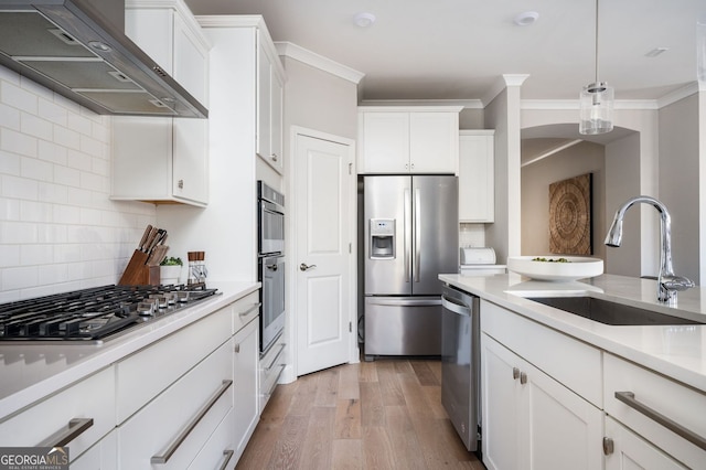 kitchen featuring white cabinets, light wood-style flooring, a sink, wall chimney range hood, and appliances with stainless steel finishes