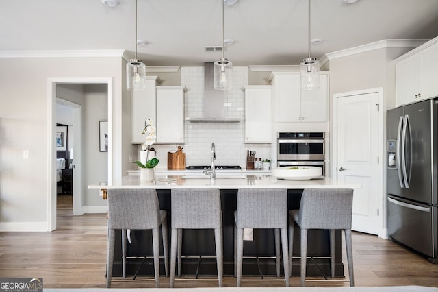 kitchen with wall chimney range hood, stainless steel refrigerator with ice dispenser, crown molding, and a kitchen breakfast bar