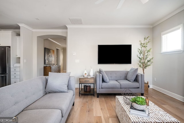 living room with ornamental molding, ceiling fan, and light hardwood / wood-style floors