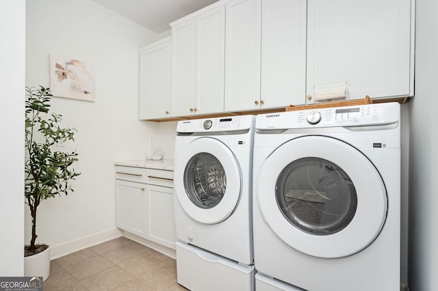 clothes washing area featuring washing machine and clothes dryer, cabinet space, and baseboards