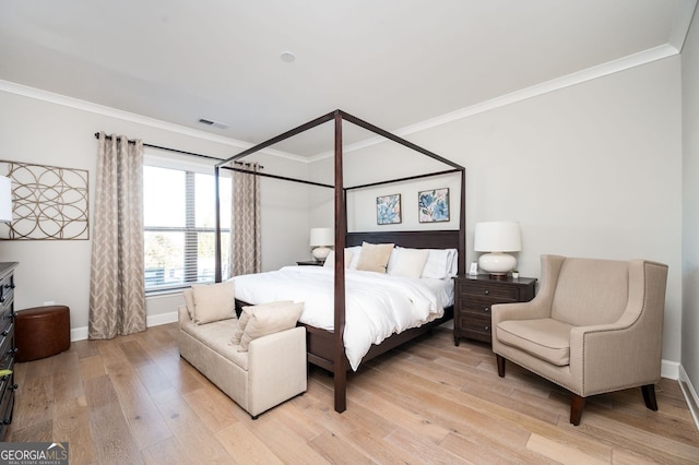 bedroom featuring baseboards, crown molding, light wood-style floors, and visible vents