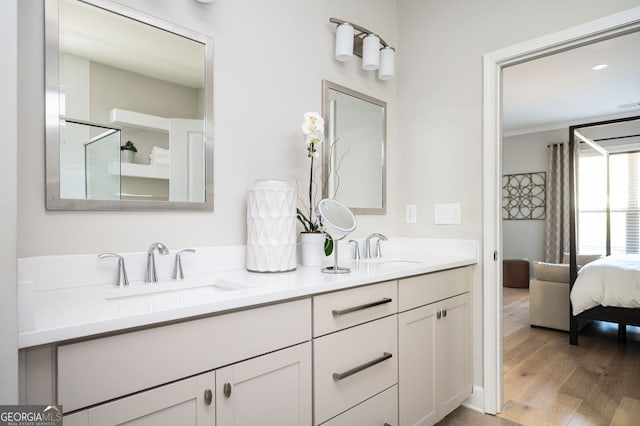 bathroom with double vanity, ensuite bathroom, wood finished floors, and a sink