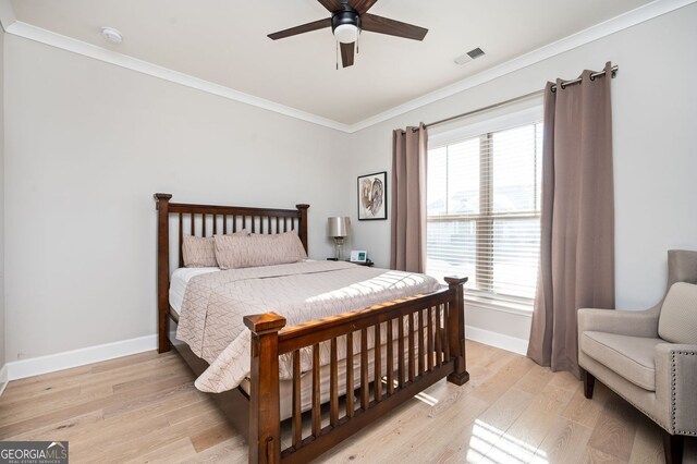 bedroom with crown molding, multiple windows, light wood finished floors, baseboards, and visible vents