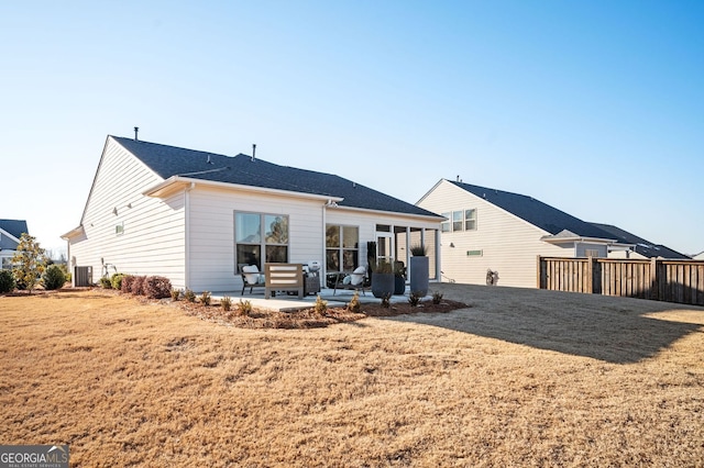 back of property featuring a lawn, central AC unit, a patio area, and a shingled roof