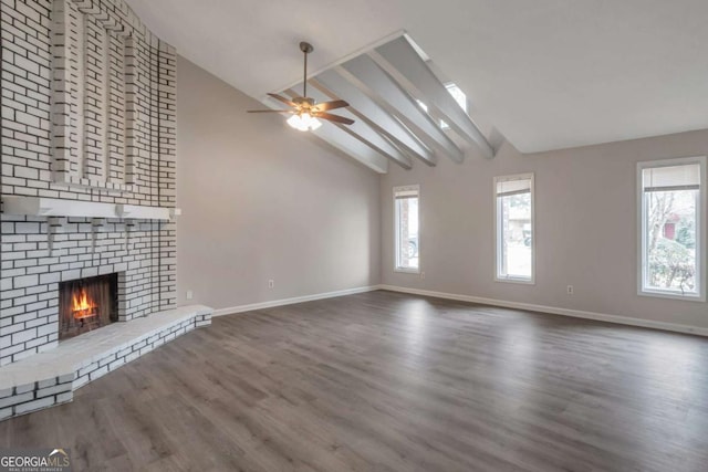 unfurnished living room with dark hardwood / wood-style flooring, vaulted ceiling, a brick fireplace, and a wealth of natural light