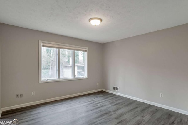 unfurnished room with dark wood-type flooring and a textured ceiling