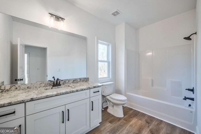 full bathroom featuring wood-type flooring, toilet, bathing tub / shower combination, and vanity