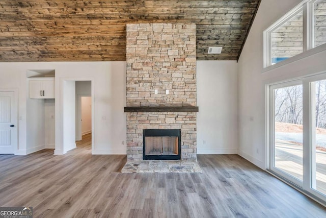 unfurnished living room with a stone fireplace, high vaulted ceiling, and light wood-type flooring