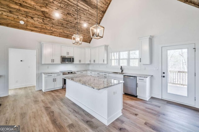 kitchen with white cabinetry, appliances with stainless steel finishes, high vaulted ceiling, and a kitchen island