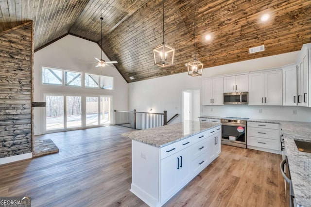 kitchen featuring pendant lighting, appliances with stainless steel finishes, white cabinetry, high vaulted ceiling, and a kitchen island