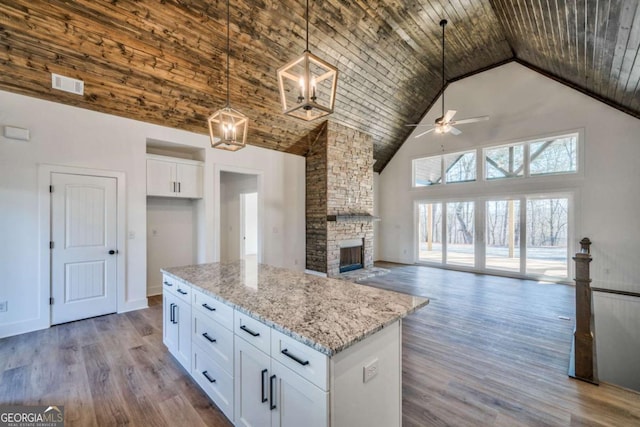 kitchen with pendant lighting, light hardwood / wood-style flooring, white cabinetry, high vaulted ceiling, and light stone countertops