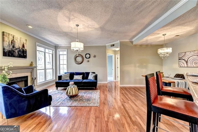 living room with crown molding, a chandelier, a textured ceiling, and hardwood / wood-style flooring