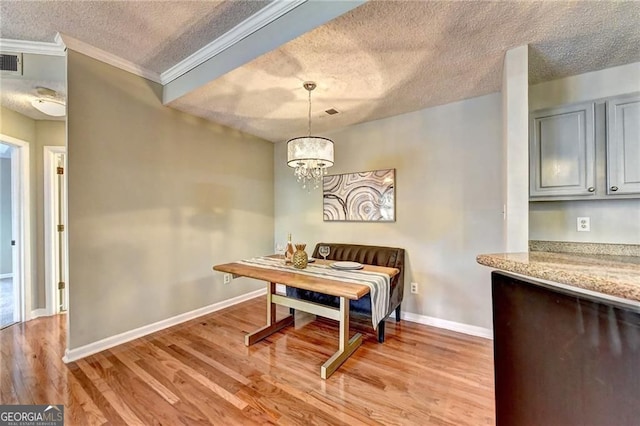 dining room with a chandelier, a textured ceiling, ornamental molding, breakfast area, and light hardwood / wood-style floors