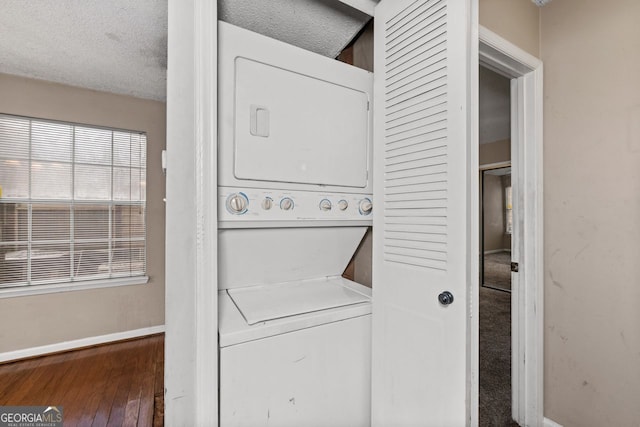 clothes washing area featuring stacked washer / dryer, dark hardwood / wood-style flooring, and a textured ceiling