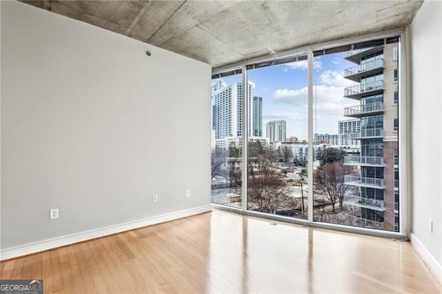 950 W Peachtree St NW Unit 812, Atlanta, GA 30309 - spare room with a view of skyline, wood finished floors, baseboards, and floor to ceiling windows