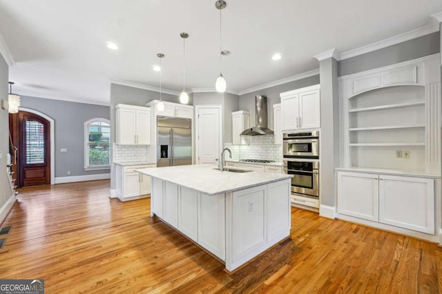 kitchen with white cabinetry, appliances with stainless steel finishes, pendant lighting, and wall chimney exhaust hood