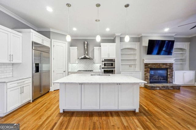 kitchen with wall chimney exhaust hood, appliances with stainless steel finishes, decorative backsplash, and white cabinets