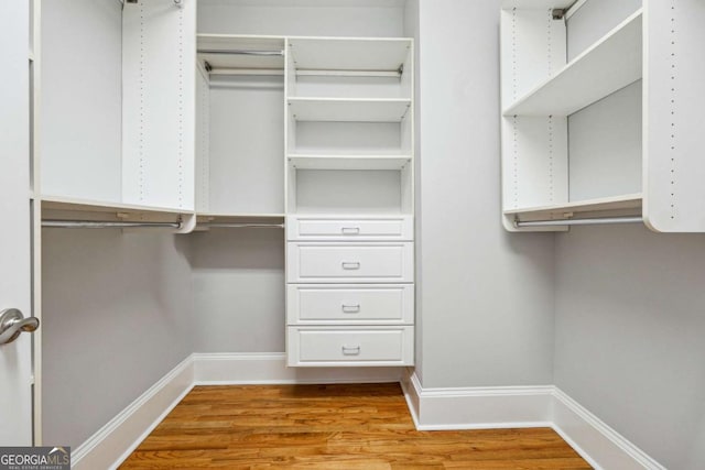 walk in closet with light hardwood / wood-style floors