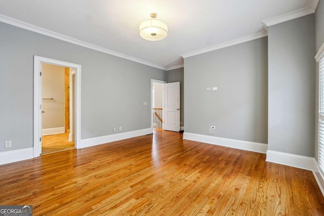 unfurnished bedroom with a walk in closet, ornamental molding, and wood-type flooring