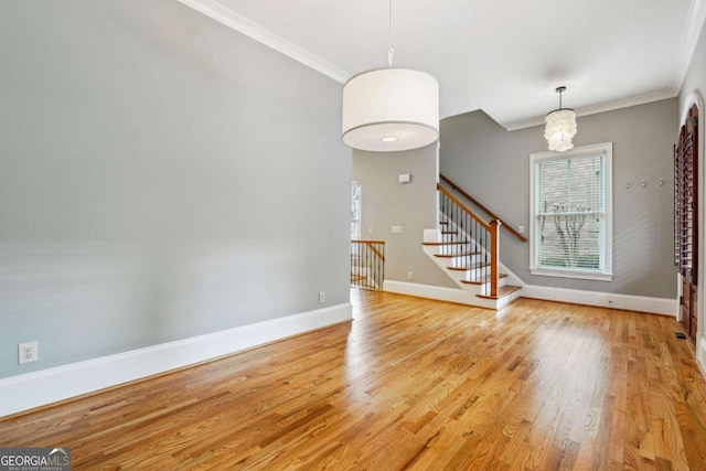 empty room featuring crown molding, a notable chandelier, and light hardwood / wood-style floors