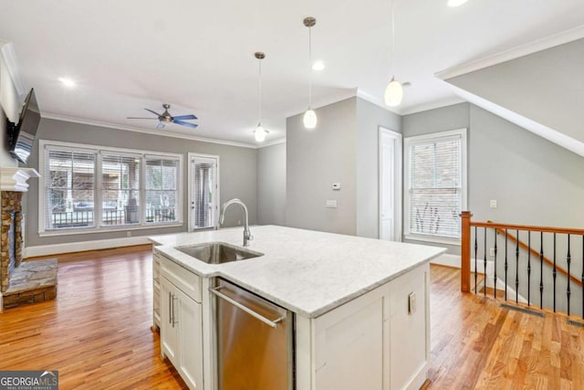 kitchen with a fireplace, dishwasher, sink, white cabinets, and a kitchen island with sink