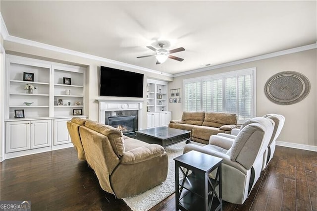 living room featuring built in shelves, crown molding, dark hardwood / wood-style floors, ceiling fan, and a high end fireplace