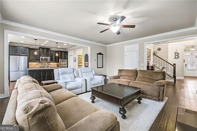 living room featuring dark hardwood / wood-style flooring, crown molding, and ceiling fan